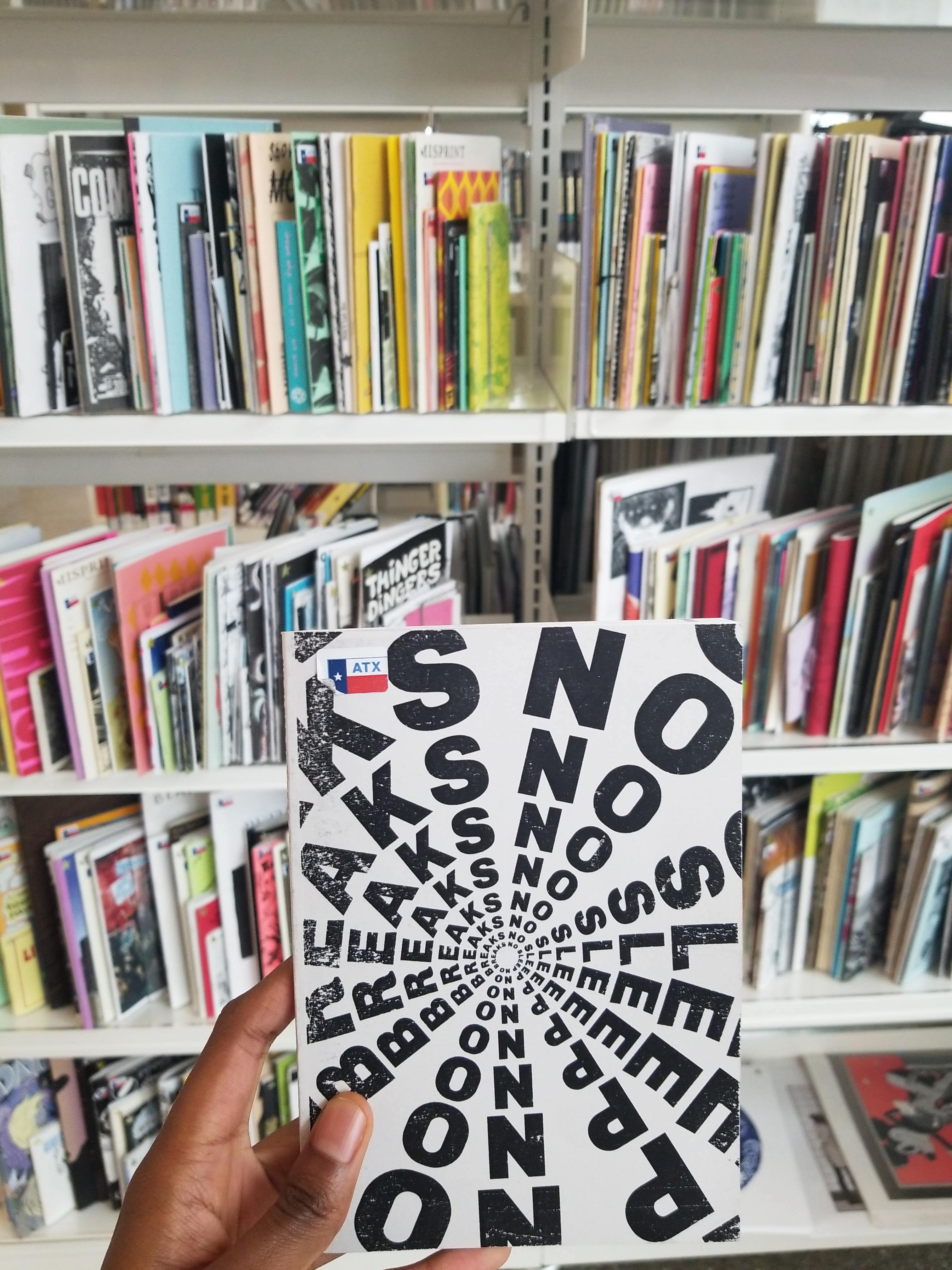 My hand holding a copy of NSNB at the Austin Public Library.